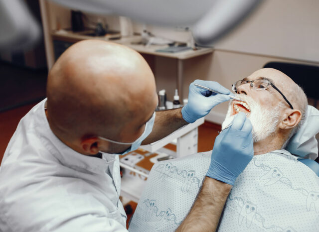 dentista che mette un impianto senza bucare l'osso a un vecchio signore