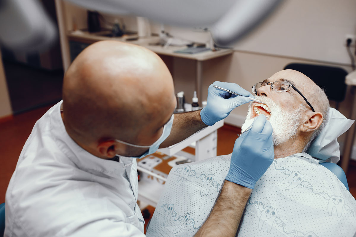 dentista che mette un impianto senza bucare l'osso a un vecchio signore